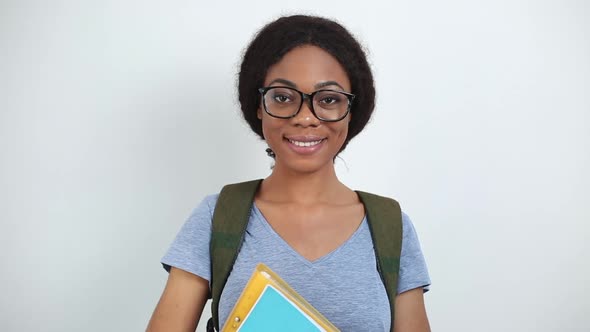 Portrait of a smiling African American student girl. Happy black woman in glasses with books