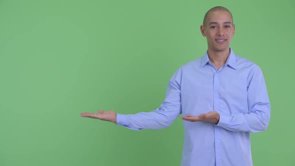 Happy Bald Multi Ethnic Businessman Showing Something and Giving Thumbs Up