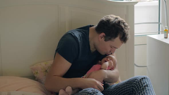 Loving Father Holding Newborn Daughter and Kissing Her