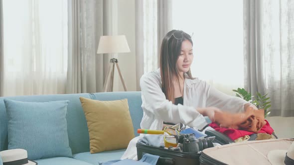 Asian Young Woman Packing Clothes In Suitcase At Home, Preparing For Vacation