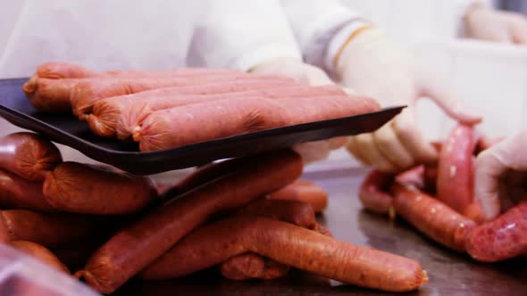 Butchers packing sausages in container
