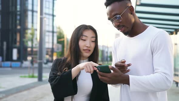 Mixed Race Friends which Standing Together on Tram Stop and Using Phone