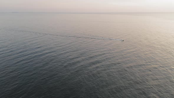 A boat motors along a calm sea during a winter sunrise off the coast of Maine AERIAL