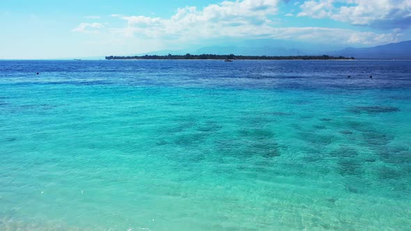 Wide angle birds eye island view of a paradise sunny white sand beach and blue sea background in 4K