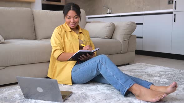 Calm AfricanAmerican Woman Sits on the Floor in Cozy Living Room with a Laptop alt
