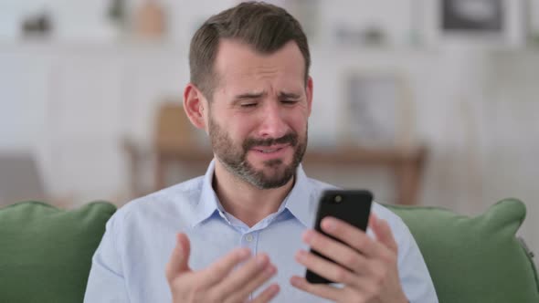 Young Man Reacting To Loss on Smartphone 