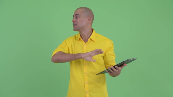 Happy Handsome Bald Businessman Talking While Holding Clipboard