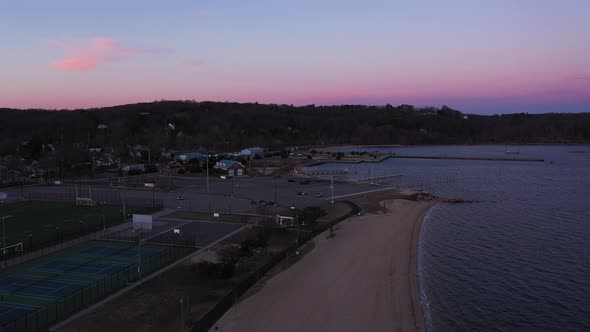 an aerial shot over a bay during a beautiful sunrise. It is golden hour and the sky is pink and blue