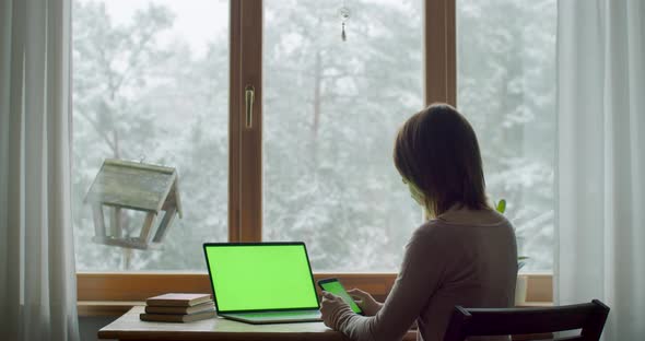 Unrecognizable Caucasian Girl Using Mobile Phone While Working on Laptop Indoors Slow Motion