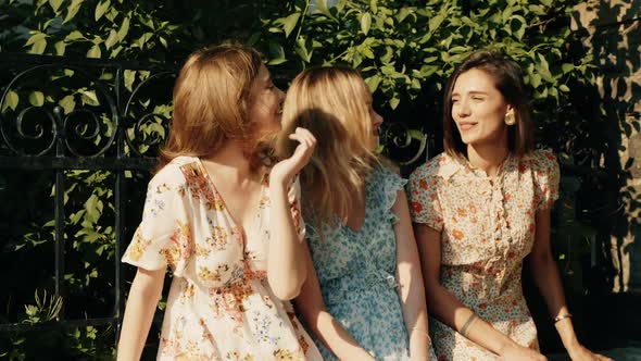 Three young beautiful girls posing outdoors at summer sunny day