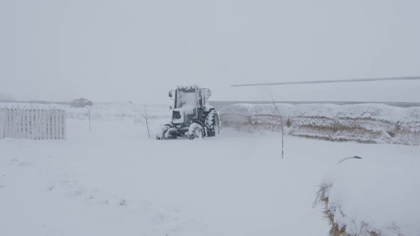 Tractor parked in field near hay in winter season.