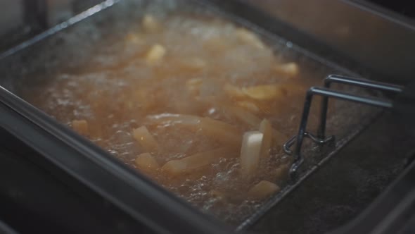 French Fries Fried in a Wire Basket in Hot Oil