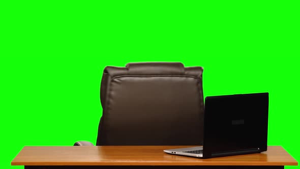 Empty Office. Leather Business Chair Rotating Near a Table with a Laptop. Green Screen.