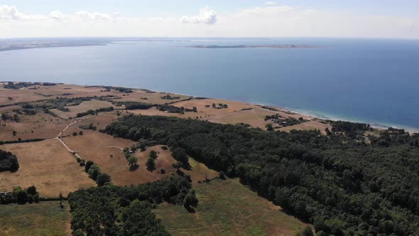 Aerial view of the coastline of Sejerøbugten with hills, fields and ocean.