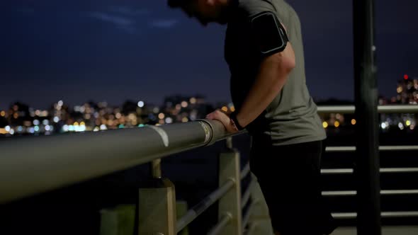 Young Male Sportsman with Athletic Body is Running on the Pier Near the Sailing Ship at Night