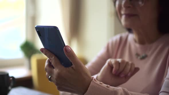 Woman Uses Smartphone and Communicates While Sitting at Table in Home Room