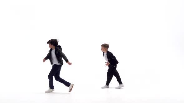 Little Boys Are Dancing a Modern Dance on the White Background in Black Leather Jackets and Jeans