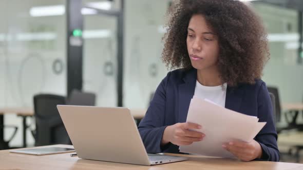 African Businesswoman with Laptop Reading Documents