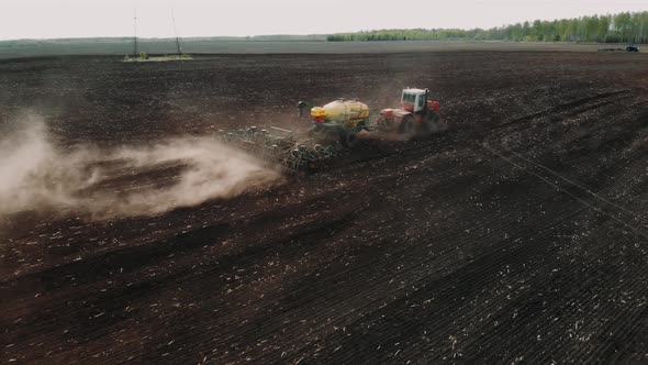 Agriculture Tractor Sowing Seeds and Cultivating Field in Late Afternoon. Agricultural Tillage