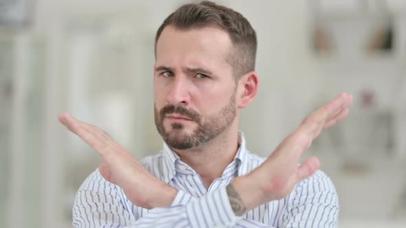 Portrait of Young Man Saying No with Arm Gesture