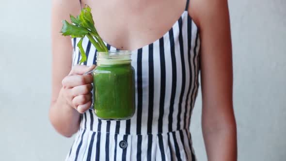 Woman holding a glass with celery juice