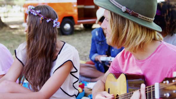 Man playing guitar for his friends at a music festival 4k