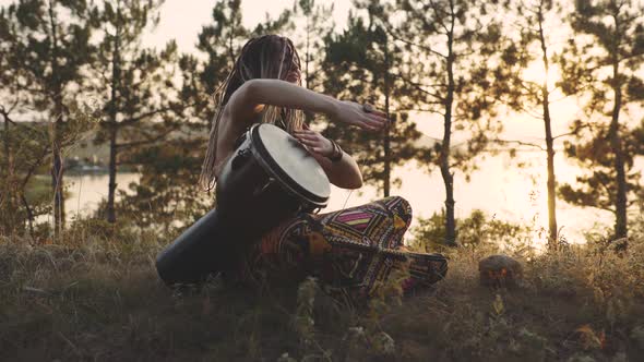 Beautiful Young Hippie Woman with Dreadlocks Playing on Djembe