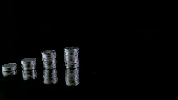 Stop Motion Animation Raising of Coins Stacks on Black Background and Coin Into a Clear Glass Jar