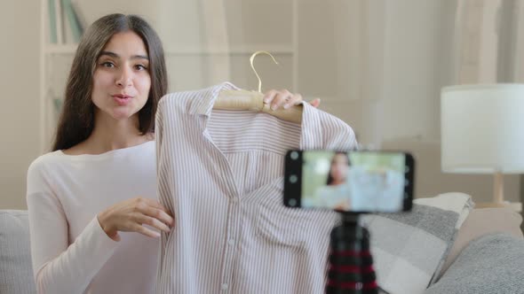 Young Arabic Beautiful Blogger Sits Front of Mobile Phone on Tripod Records Fashion Clothing Video