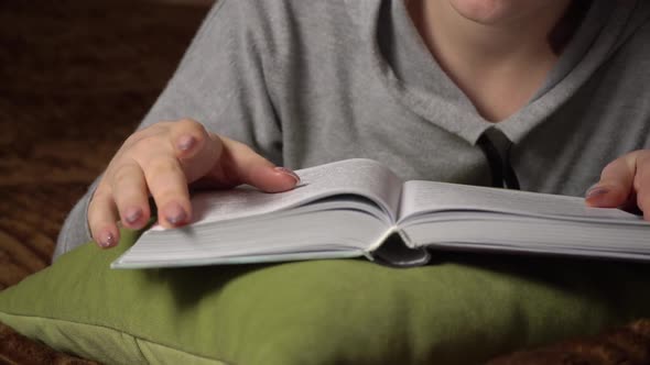 Beautiful Girl Reads a Book Comfortably While Lying in Bed