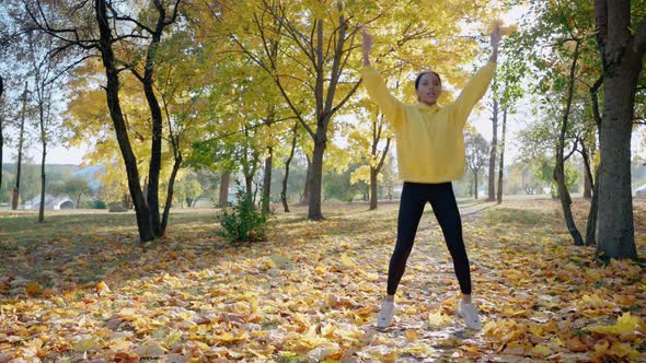 Girl Doing Jumping Jack and Stretching Before Morning Run at the Park in Autumn