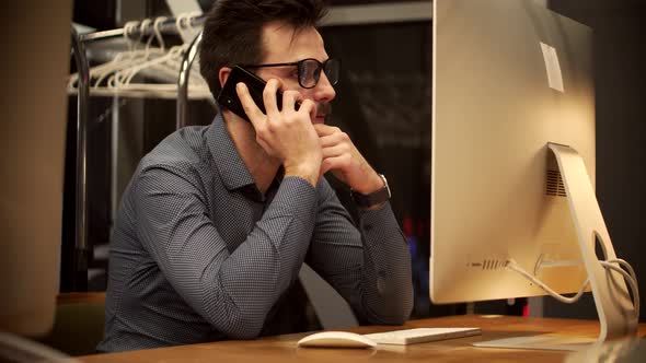 Overtime Work In Office.Handsome Businessman On Computer Working In Office And Talking On Smartphone