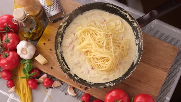 Making Pasta Carbonara Putting Spaghetti Into Sauce Made of Cream and Chopped Pancetta Bacon in