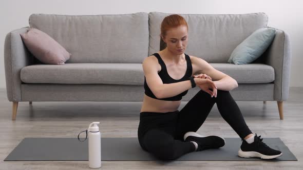 Athletic Lady Using Fitness Smartwatch After Workout Sitting At Home