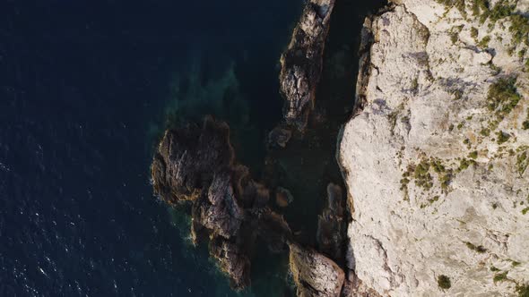 Top down view of rocky cliff by the sea and rocks.