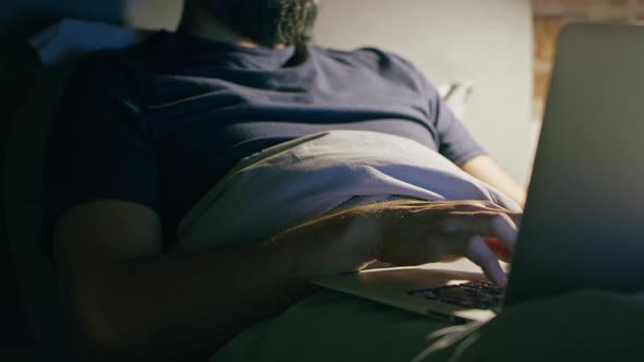 Tilt up video of man lying and working in bed. Shot with RED helium camera in 8K.