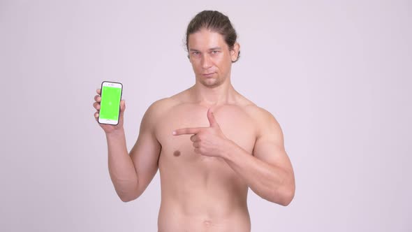 Happy Muscular Shirtless Man Showing Phone and Giving Thumbs Up