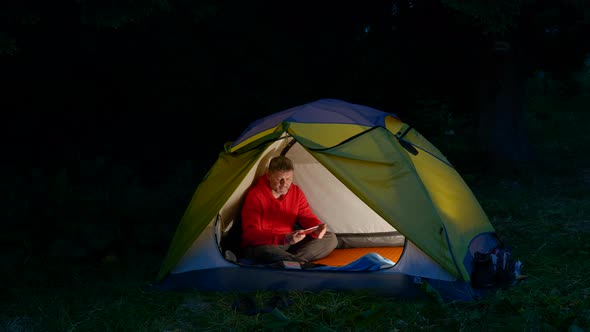 A Man in a Tent in the Night Forest
