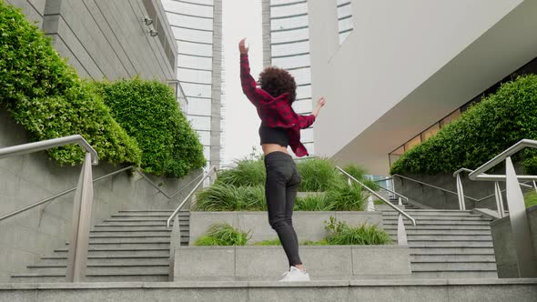 Young woman dancing in the wind among modern buildings