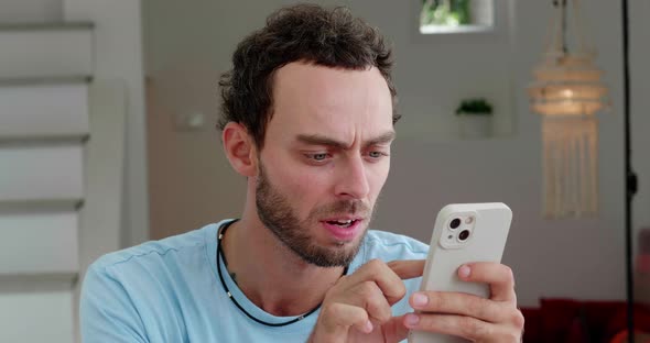 Handsome Caucasian Man in Casual Blue Tshirt Using Mobile Phone Scrolling Websites Checking News