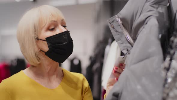 Mature Woman Shopper in Clothing Store Caucasian Female Customer in Protective Mask Chooses Clothes