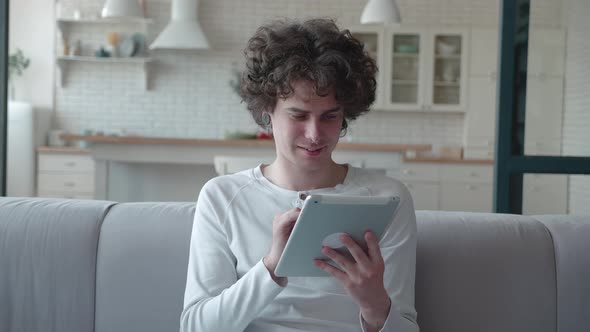 Young Professional Worker Using Digital Tablet Corporate Software Sitting in the Sofa Smiling Male