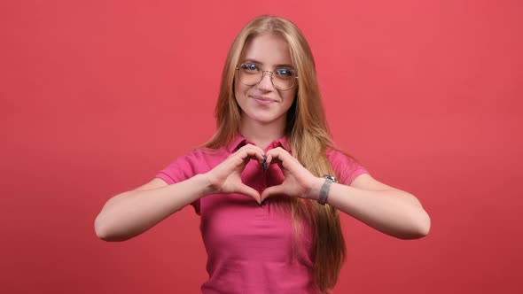 A Nice Girl Who Puts Her Hands in the Shape of a Heart and Smiles at the Camera