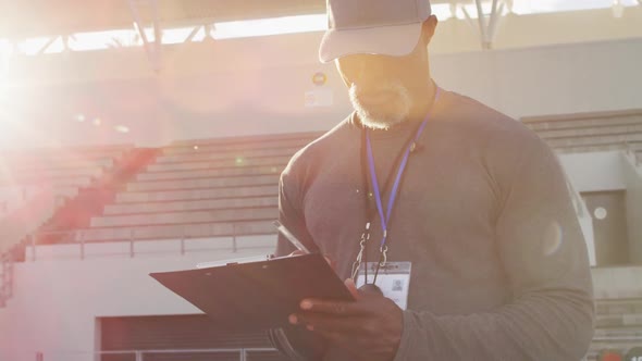 African american male coach making notes on sunny day