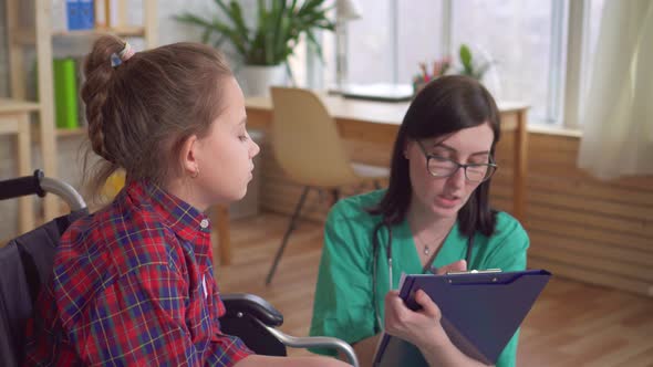 Woman Doctor Talking To a Disabled Child in a Wheelchair