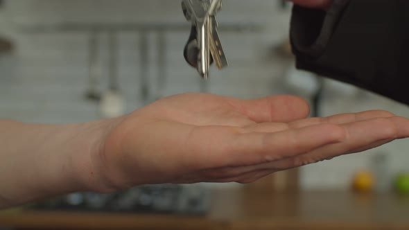 Closeup of Female Realtor Hand Giving House Key of New Home to Man