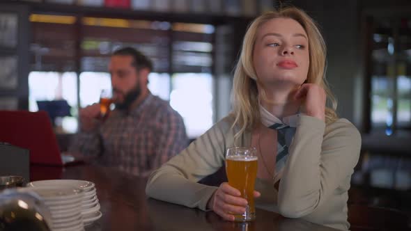 Portrait of Charming Young Slim Woman Sitting at Bar Counter with Beer Pint As Man Drinking at