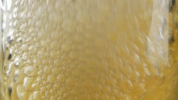 Close up of air bubbles created by someone blowing with straw into full glass of beer or soda