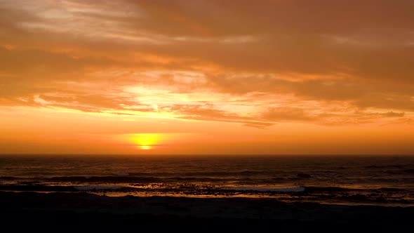 Sunset over ocean, light clouds causing impressive golden skies