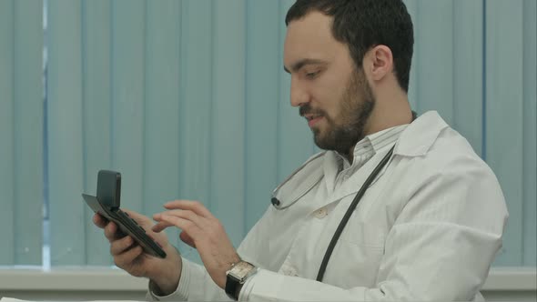 Bearded Doctor with a Calculator. Make Calculations of Price and Satisfied of It